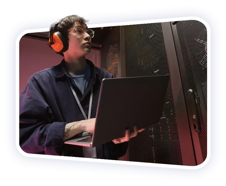 Disruptive Outsourcing Solutions a male IT engineer holding a laptop and checking the status of their servers